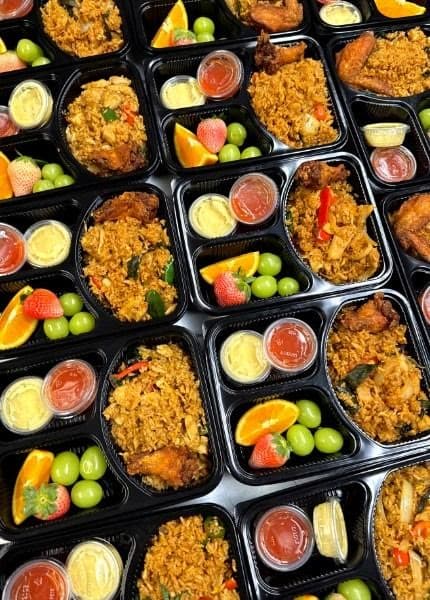 Individual boxed catering meals with fried rice, fruit, and sauces